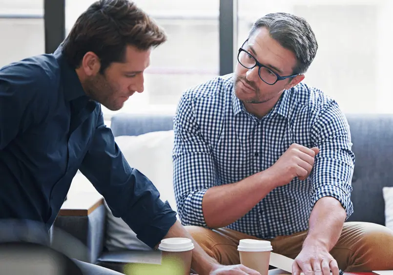 two men discussing plans over table with coffee